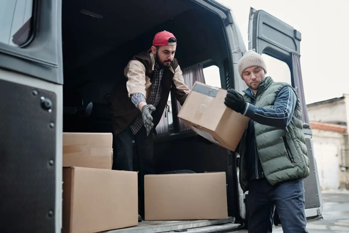 Helfer reichen sich Kartons an der offenen Ladefläche an