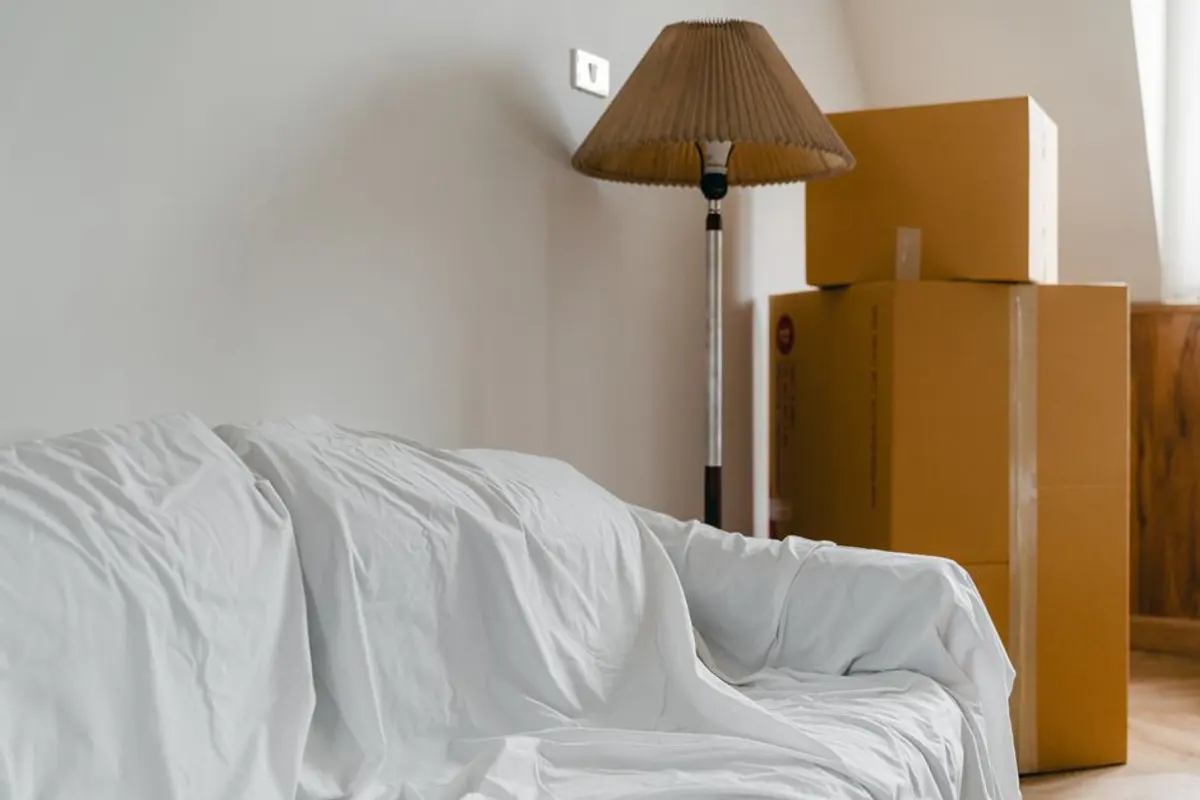 Abgedecktes Sofa und gestapelte Kartons in einer kleinen Wohnung