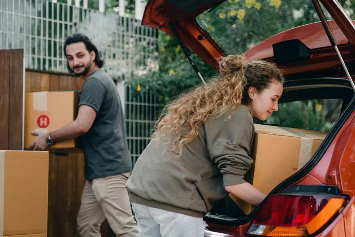 Kartons werden in den Kofferraum eines Mietwagens geladen