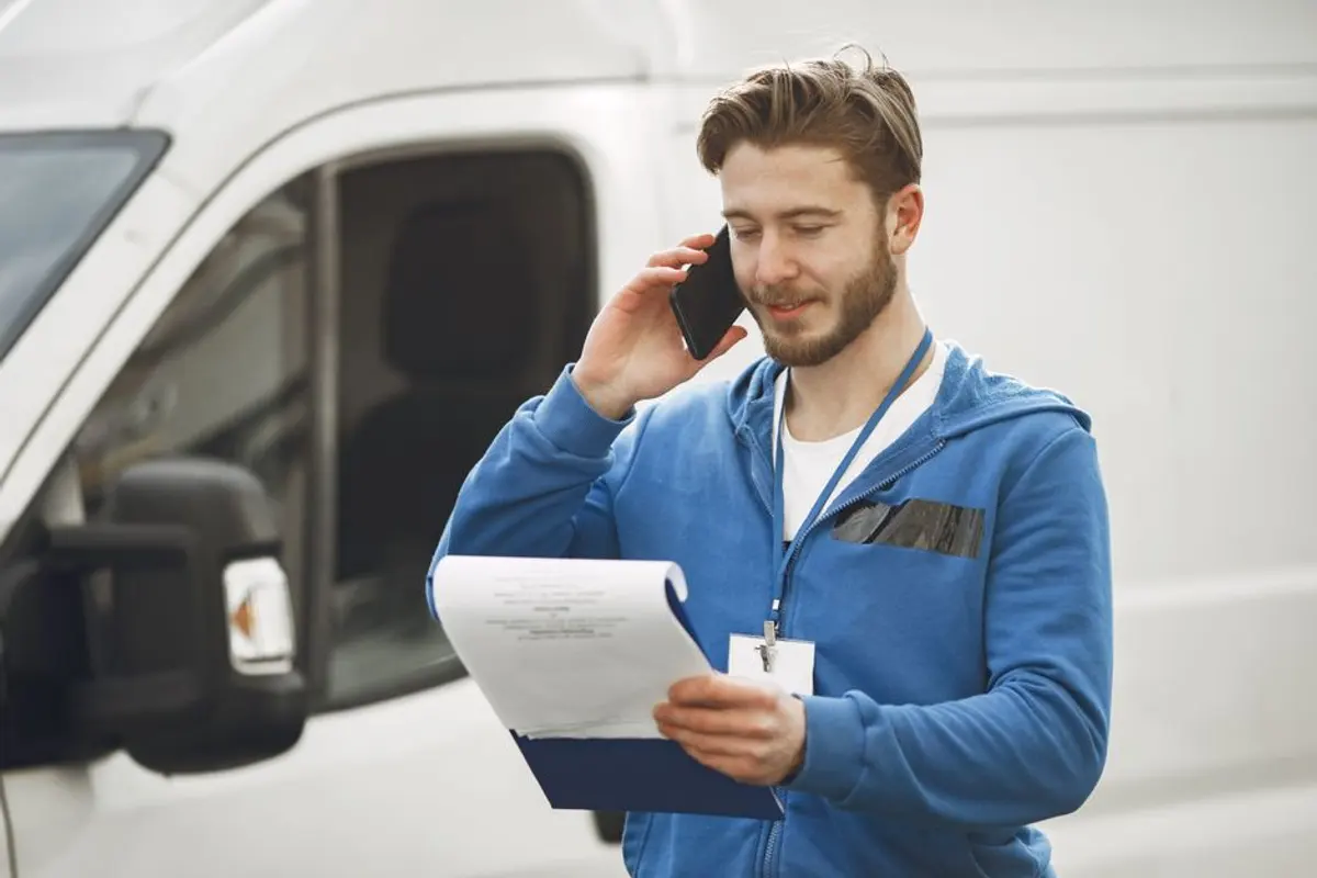 Ein Mitarbeiter geht vor dem Fahrzeug die Auftragsliste durch
