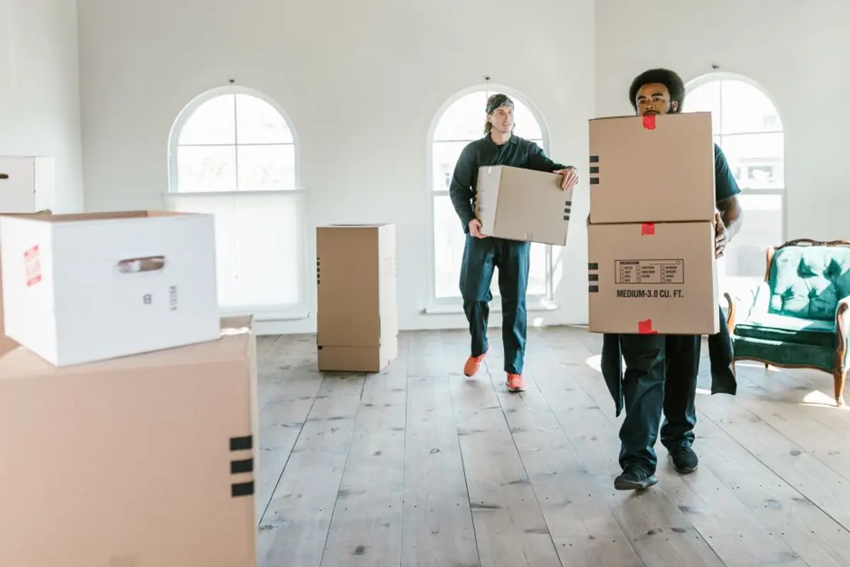 Helfer tragen gestapelte Kartons durch die leere Wohnung