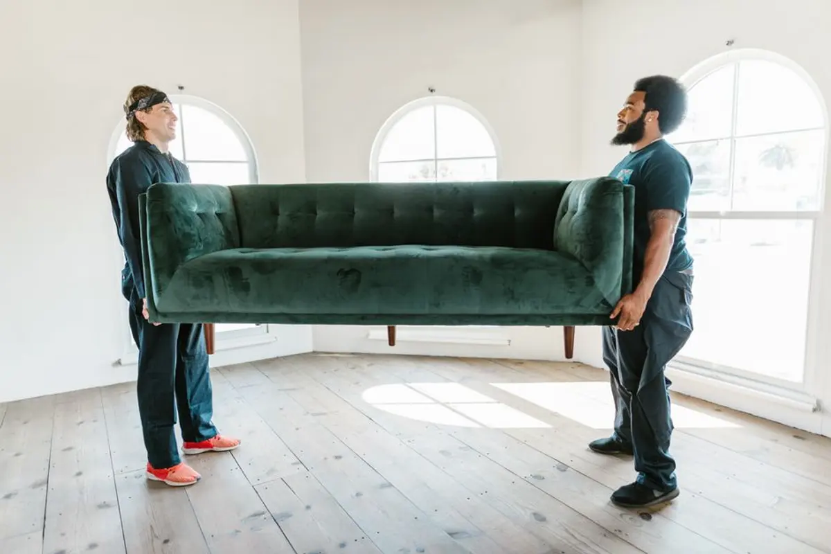 Zwei Umzugshelfer tragen gemeinsam ein Sofa